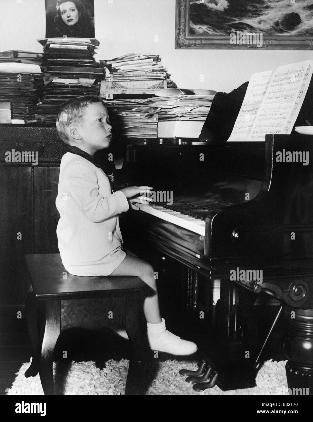 Profilo di un ragazzo seduto su uno sgabello e riproduzione di un pianoforte Foto Stock