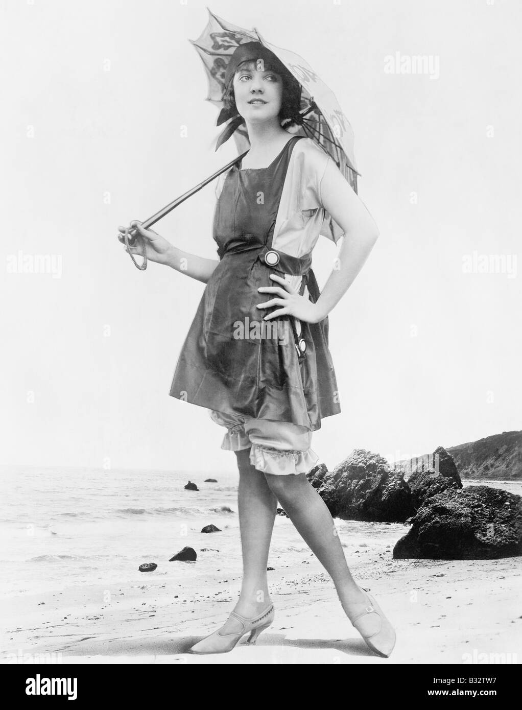 Donna con ombrellone e costume da bagno in spiaggia Foto Stock