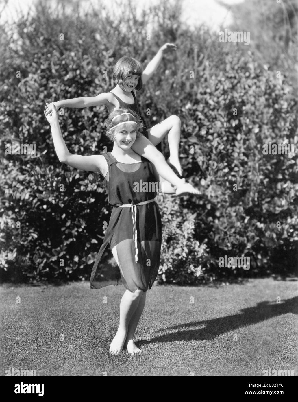 Madre e figlia facendo acrobazie in cortile Foto Stock