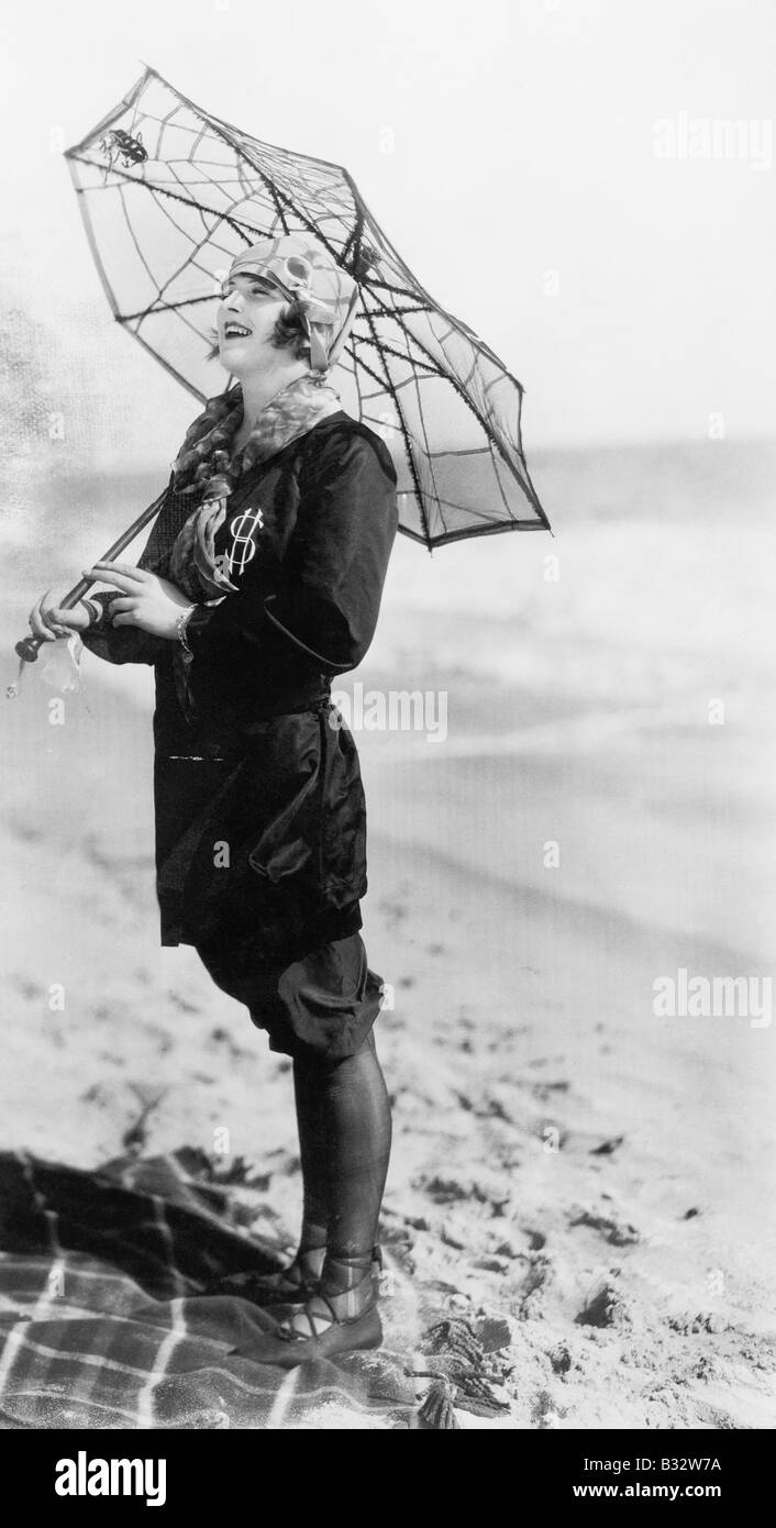 Giovane donna sulla spiaggia con un ombrello cercando come una ragnatela Foto Stock