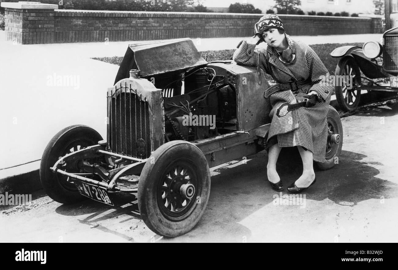 Giovane donna seduta accanto alla piccola auto guardando il motore nel credere Foto Stock