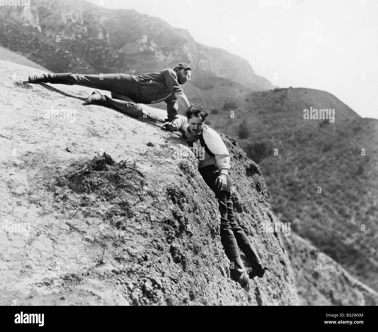 L'uomo aiutando un altro uomo cada una scogliera Foto Stock
