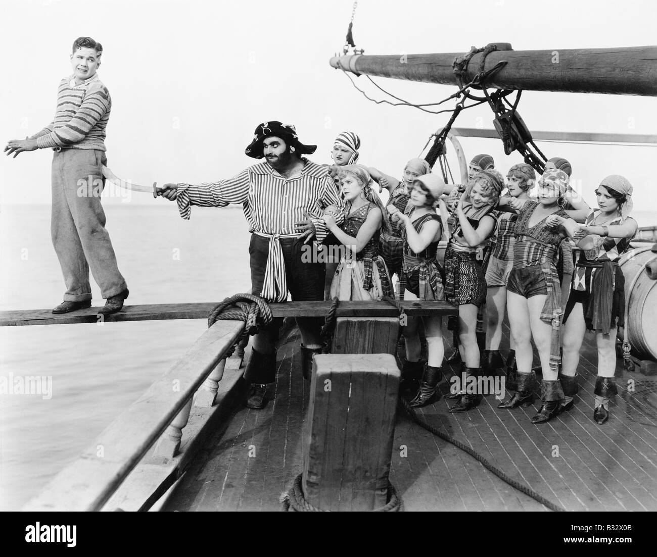 Un gruppo di pirati cercando di spingere un giovane su una tavola Foto Stock