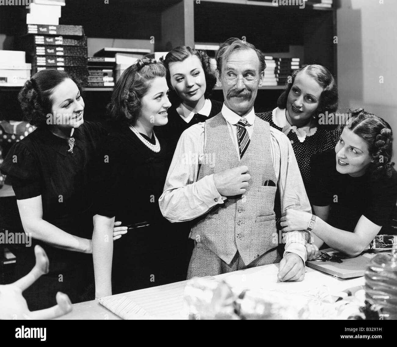 Cinque giovani donne raccogliendo attorno a un commesso in un negozio Foto Stock