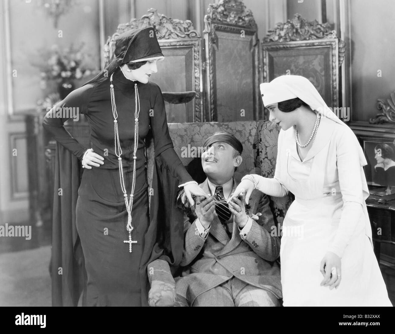 Giovane con un occhio patch di essere consolato da un infermiere e una donna religiosa Foto Stock