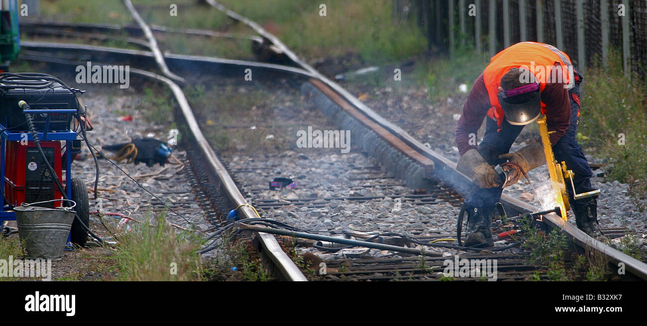 Uomo di saldatura su di un binario di una linea secondaria Foto Stock