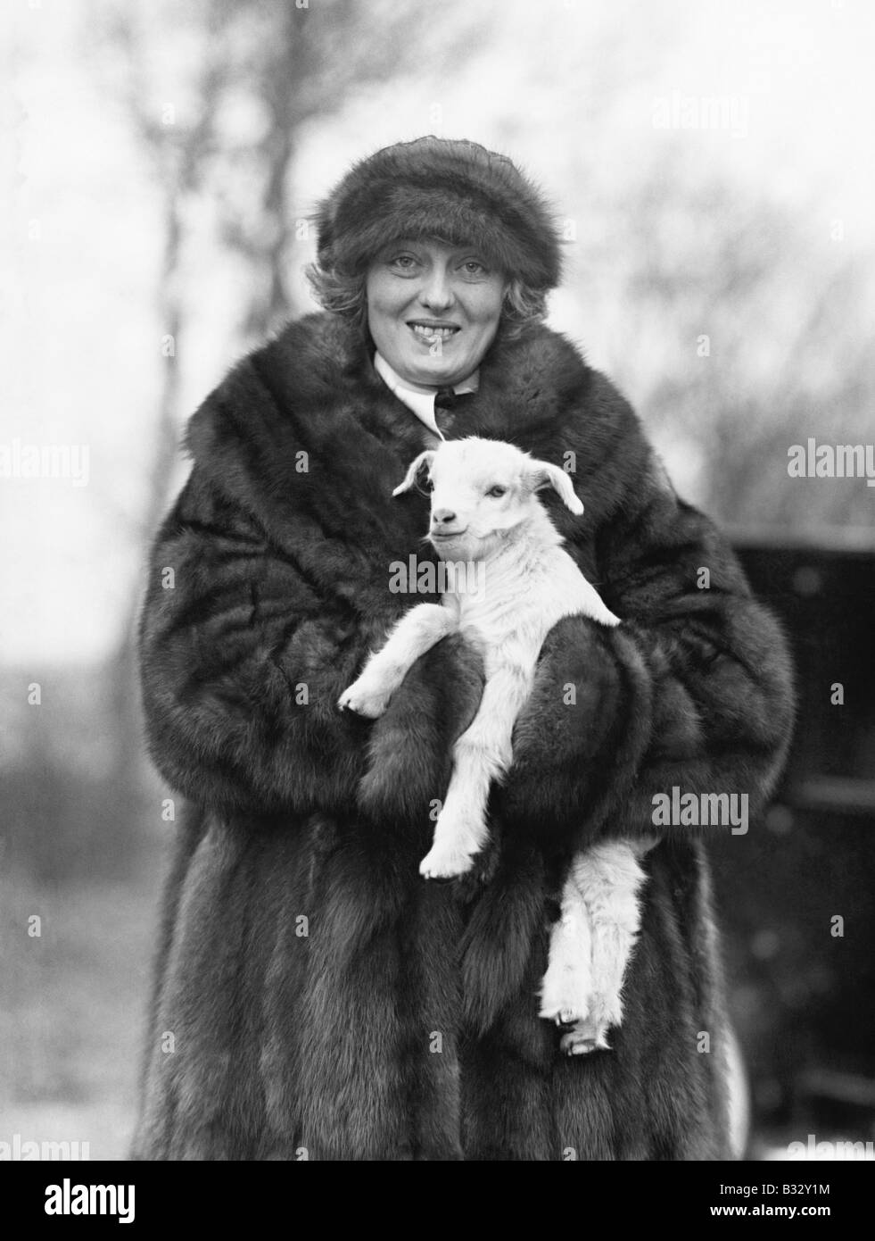 La donna in una pelliccia e hat tenendo un bimbo piccolo agnello nelle sue braccia Foto Stock