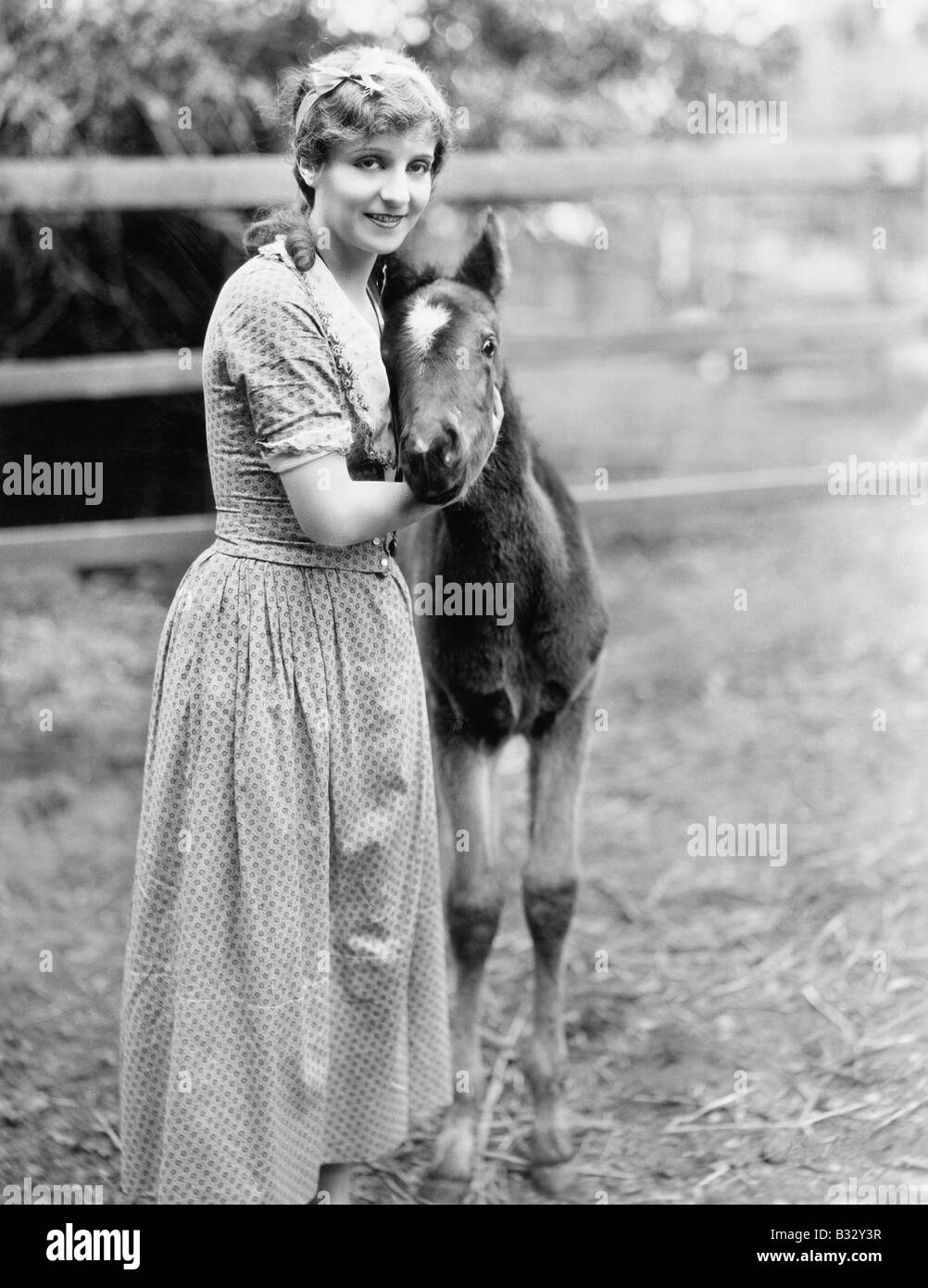 Donna in piedi accanto a un pony in un recinto per bestiame Foto Stock