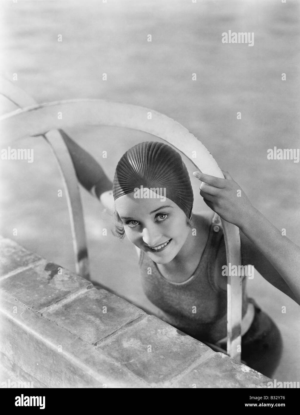 Donna arrampicata fuori da un pool Foto Stock