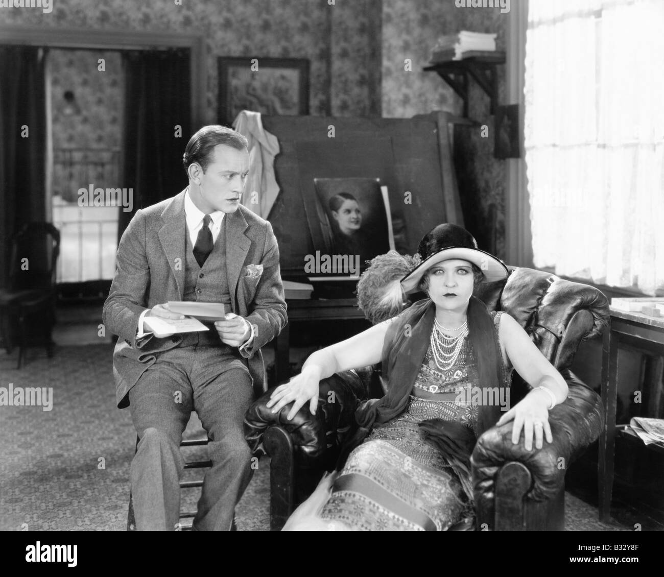 L uomo e la donna seduta in un salotto lettura di una lettera e guardando sorpreso Foto Stock