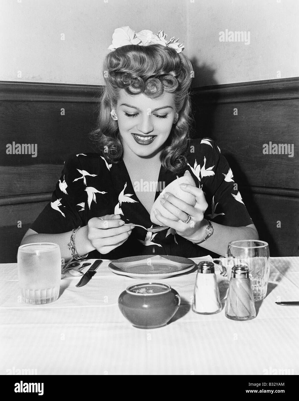 Donna seduta a un tavolo e spremendo il succo di pompelmo Foto Stock