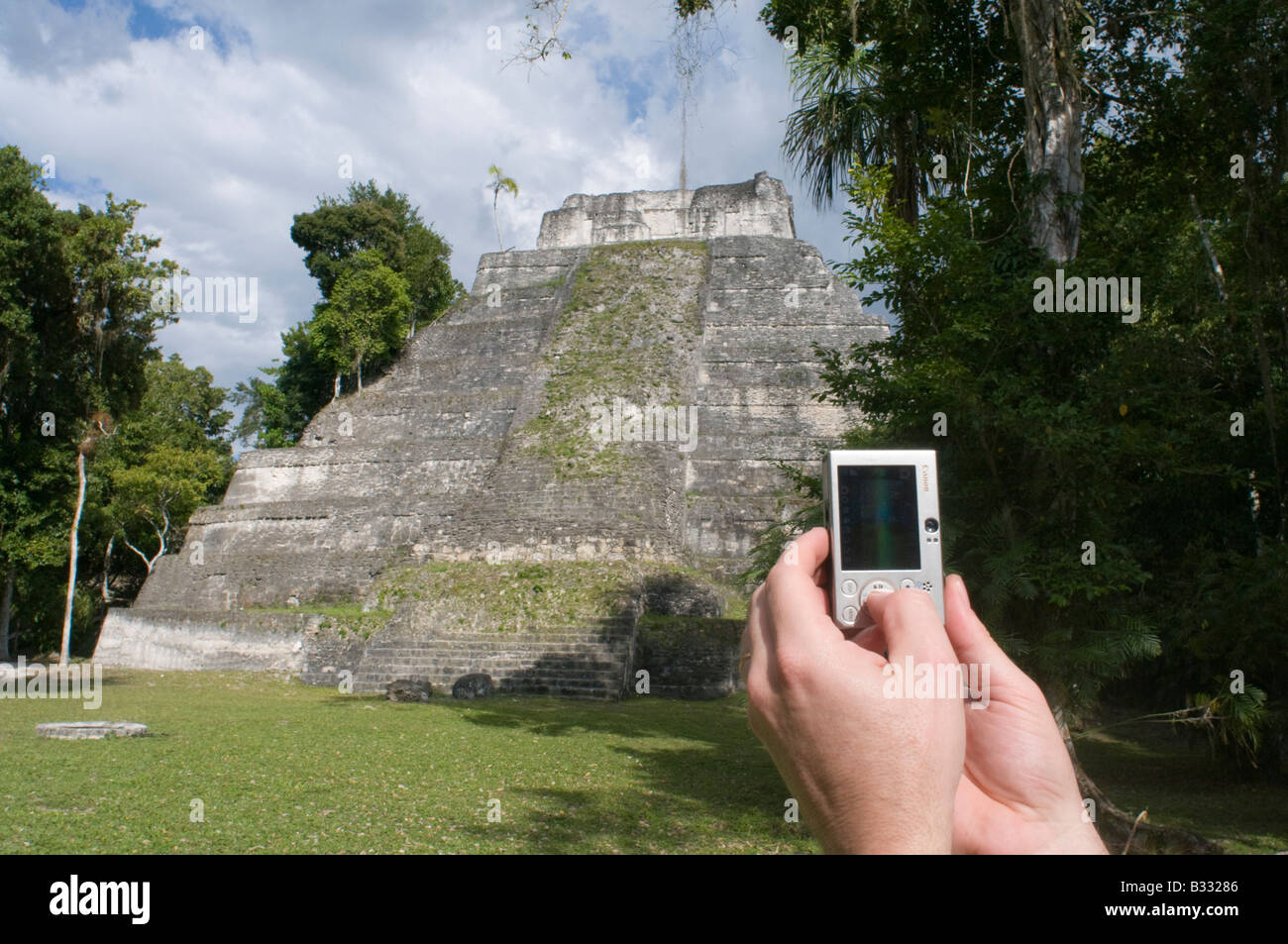 Tourist utilizzando una fotocamera digitale per fotografare un tempio Maya a Yaxha nr Tikal Guatemala Foto Stock