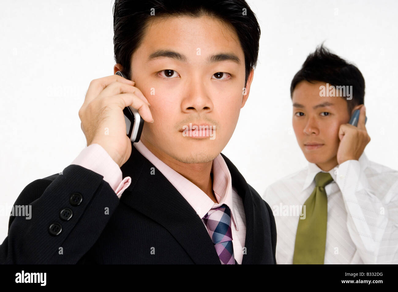Un serio imprenditore asiatico (messa a fuoco) sta di fronte ad un collega (off focus) Foto Stock