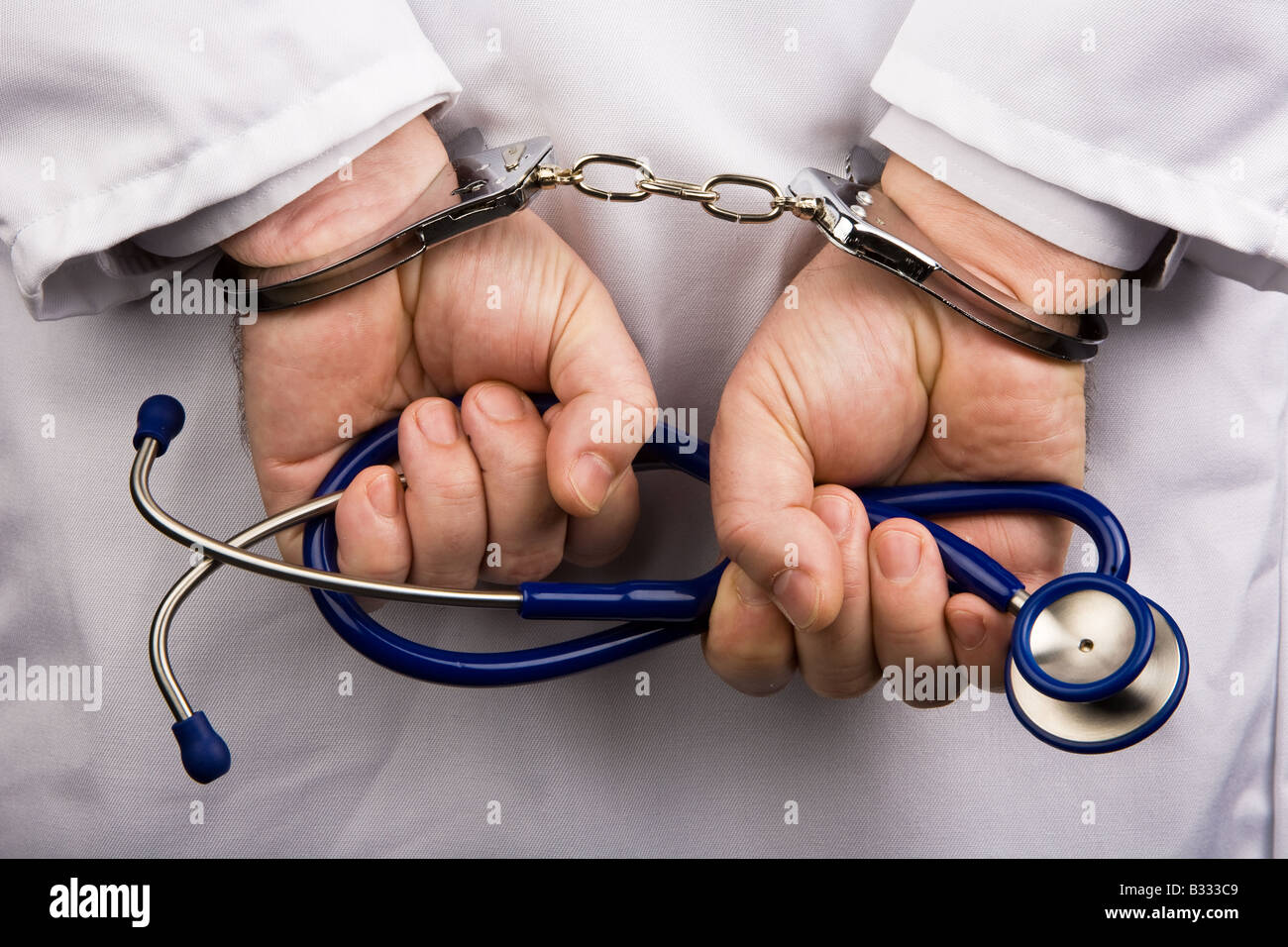 Medico con le banconote e le manette Foto Stock