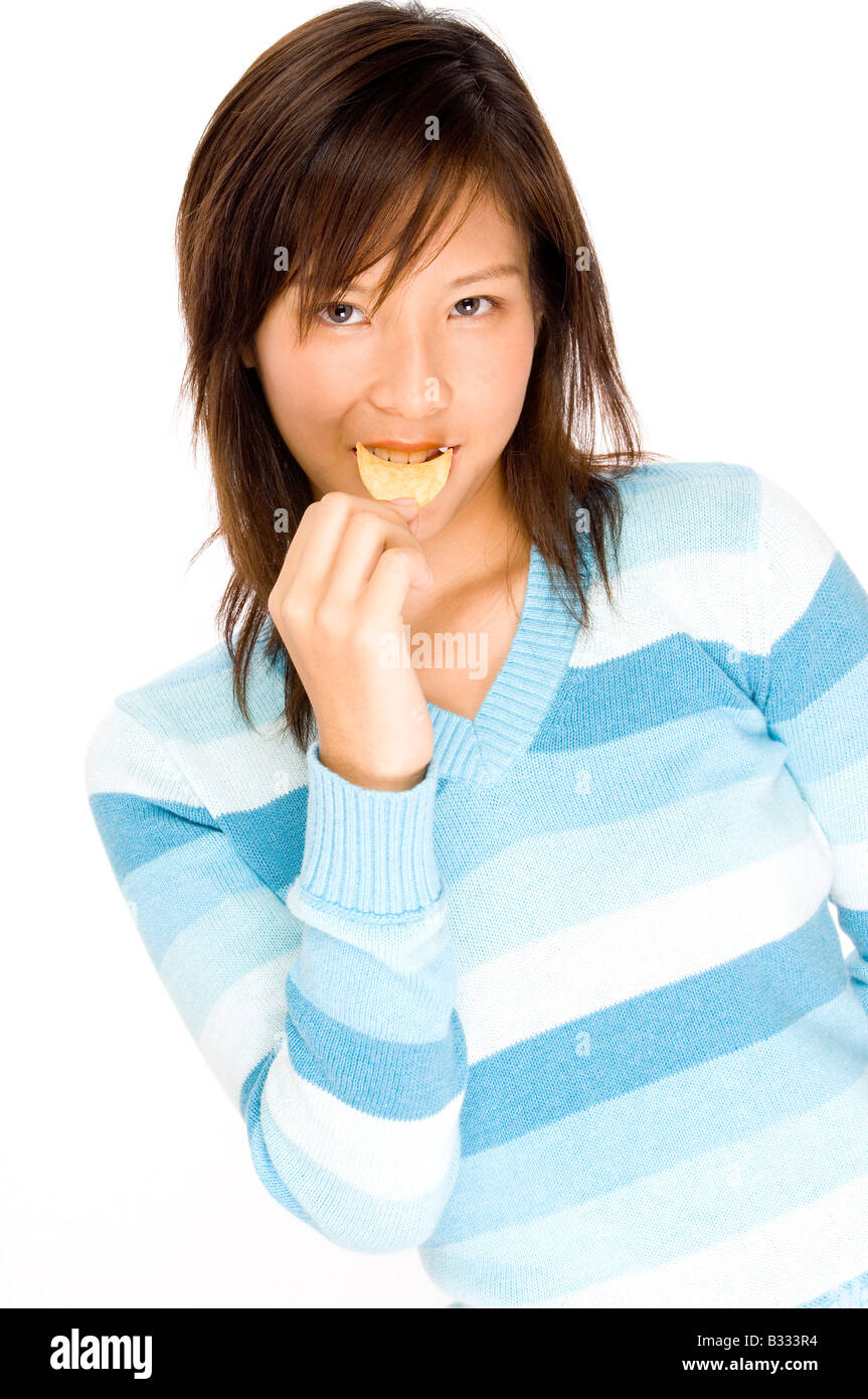 Un simpatico giovane donna asiatica mangiare patatine Foto Stock
