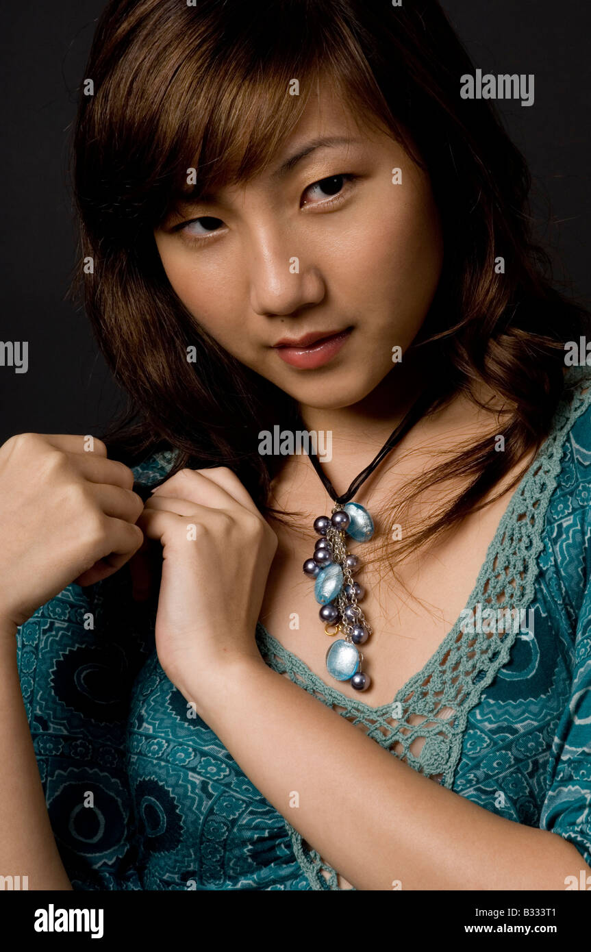 Una bellissima e misteriosa giovane donna asiatica su sfondo nero Foto Stock