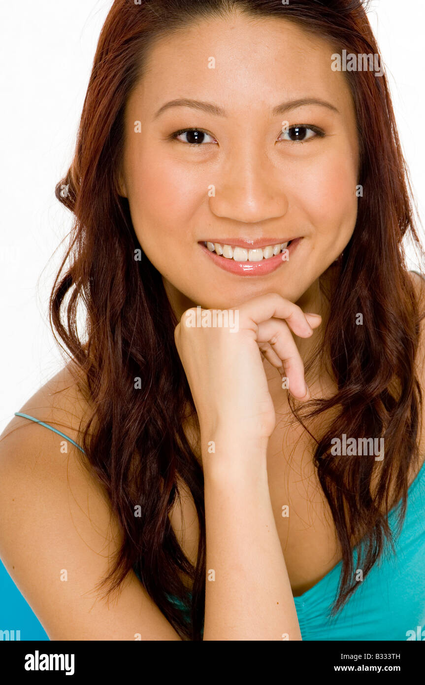 Una giovane e bella donna asiatica con mento in appoggio a portata di mano Foto Stock