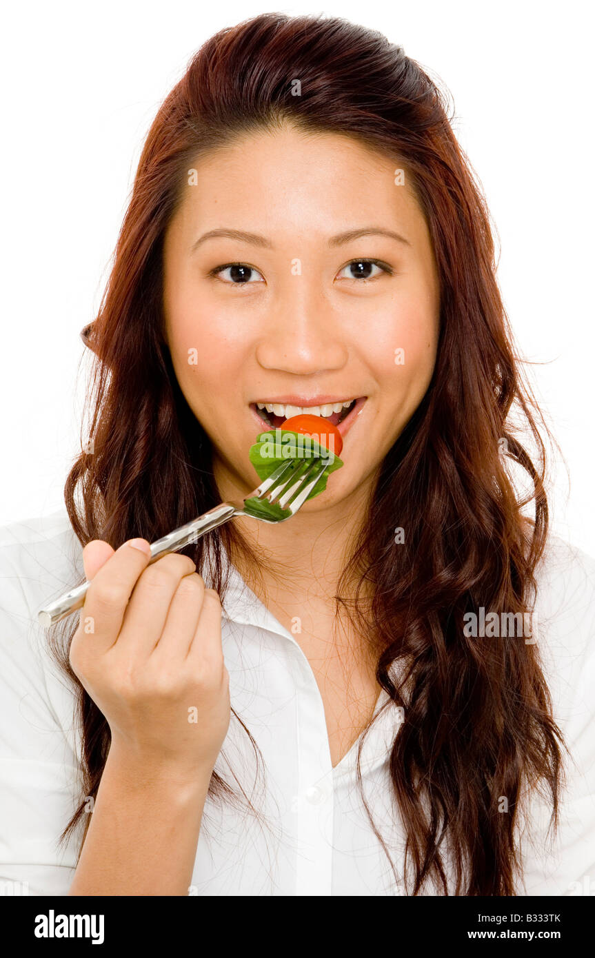 Una giovane e bella donna asiatica mangiare insalata Foto Stock