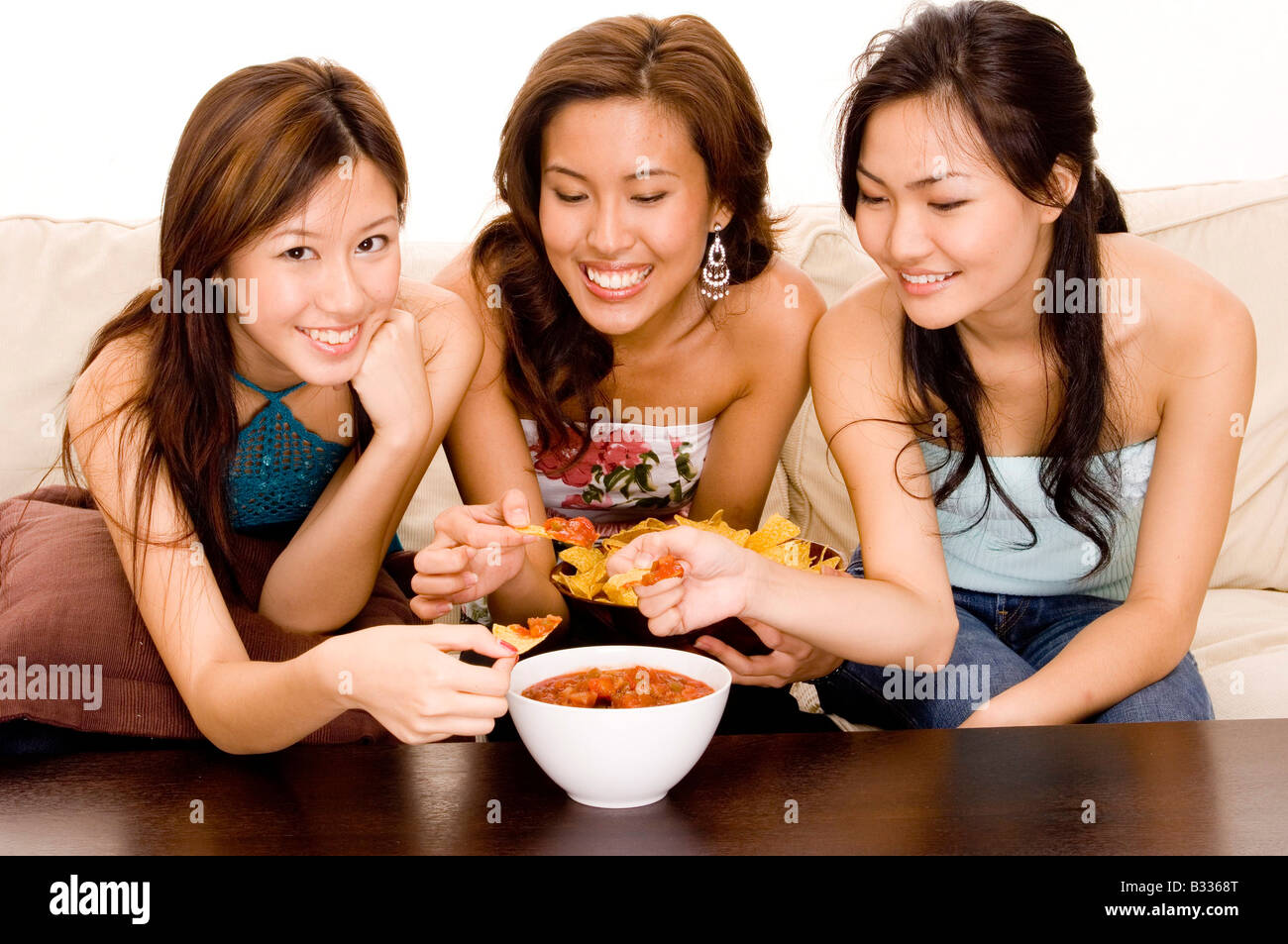 Tre donne immersione nachos in una salsa di salsa Foto Stock