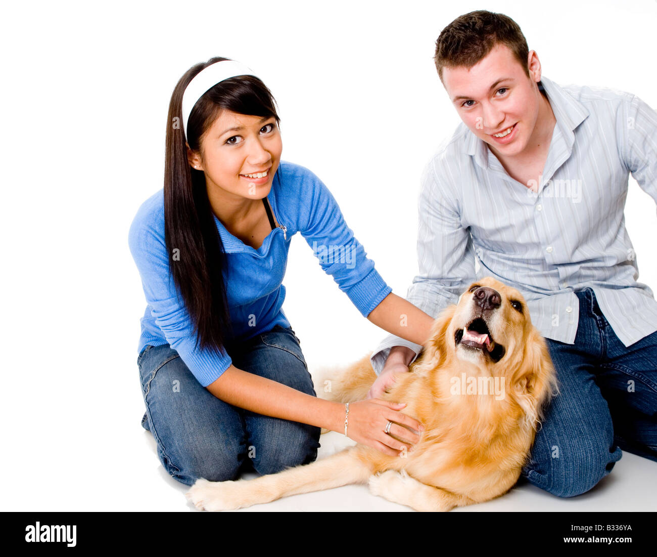 Una giovane coppia corsa il loro cane - girato in studio su sfondo bianco Foto Stock