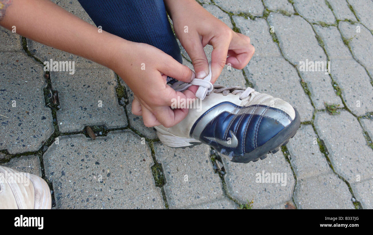 Ragazzo la sua legatura scarpe da calcio, serie immagine 3/6 Foto Stock