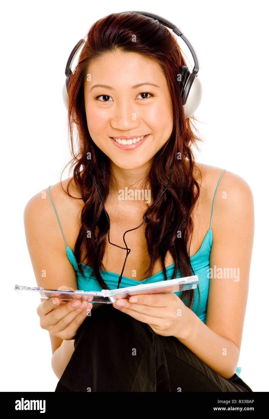 Una bella giovane donna asiatica ascolta un CD sulle cuffie Foto Stock
