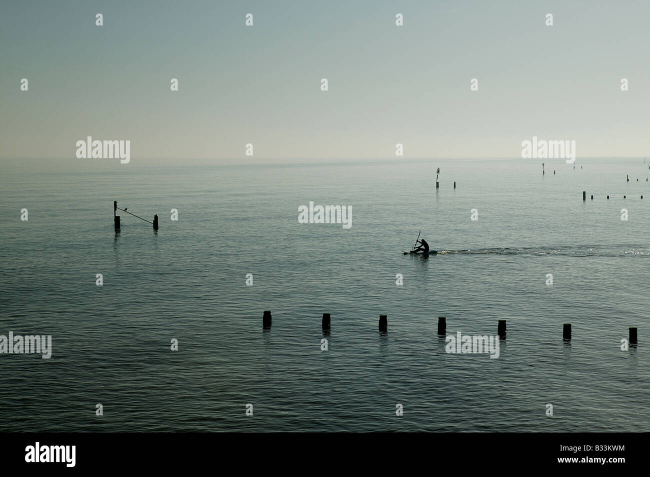 Umane singole righe in mare aperto su una tavola da surf tra i pennelli fuori dell'acqua offrendo i concetti di libertà di un nuovo Foto Stock