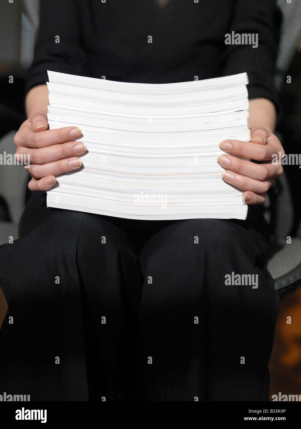 Una vista ravvicinata di mani femminili con in mano una risma di carta mentre è seduto Foto Stock