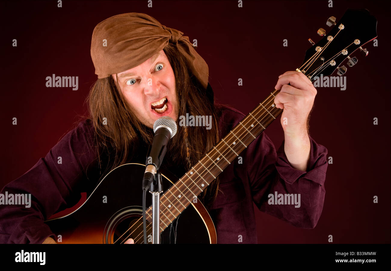 Un uomo è follemente suonare la chitarra acustica e canto Foto Stock