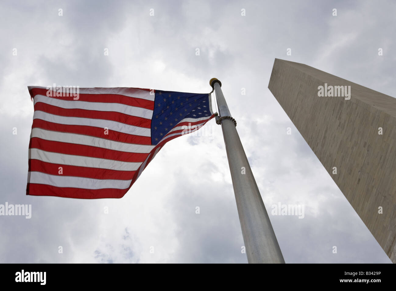 Bandiera americana soffiando adiacente al Monumento di Washington, il Mall di Washington DC, Stati Uniti d'America. Foto Stock