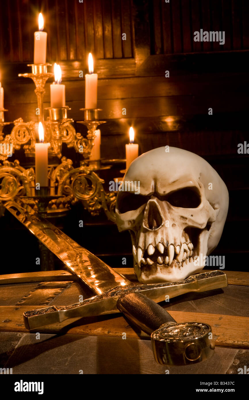 Il cranio e la spada illuminato da candele in una cappella Foto Stock