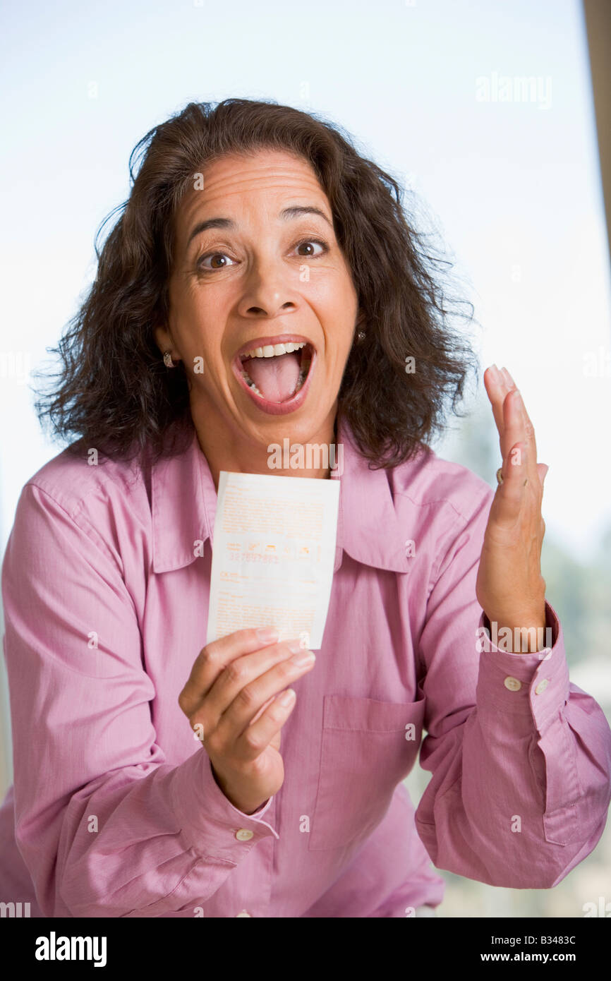 Donna con la vincita del biglietto della lotteria eccitato e sorridente Foto Stock