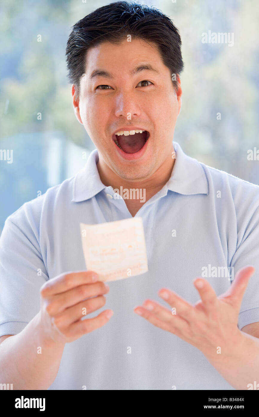 L'uomo con la vincita del biglietto della lotteria eccitato e sorridente Foto Stock