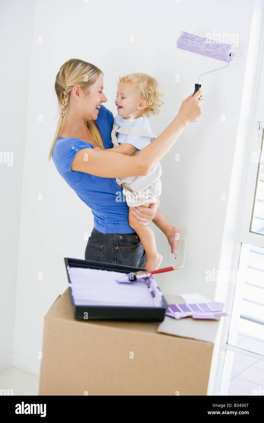 Azienda madre figlio mentre la camera di verniciatura nella nuova casa sorridente Foto Stock