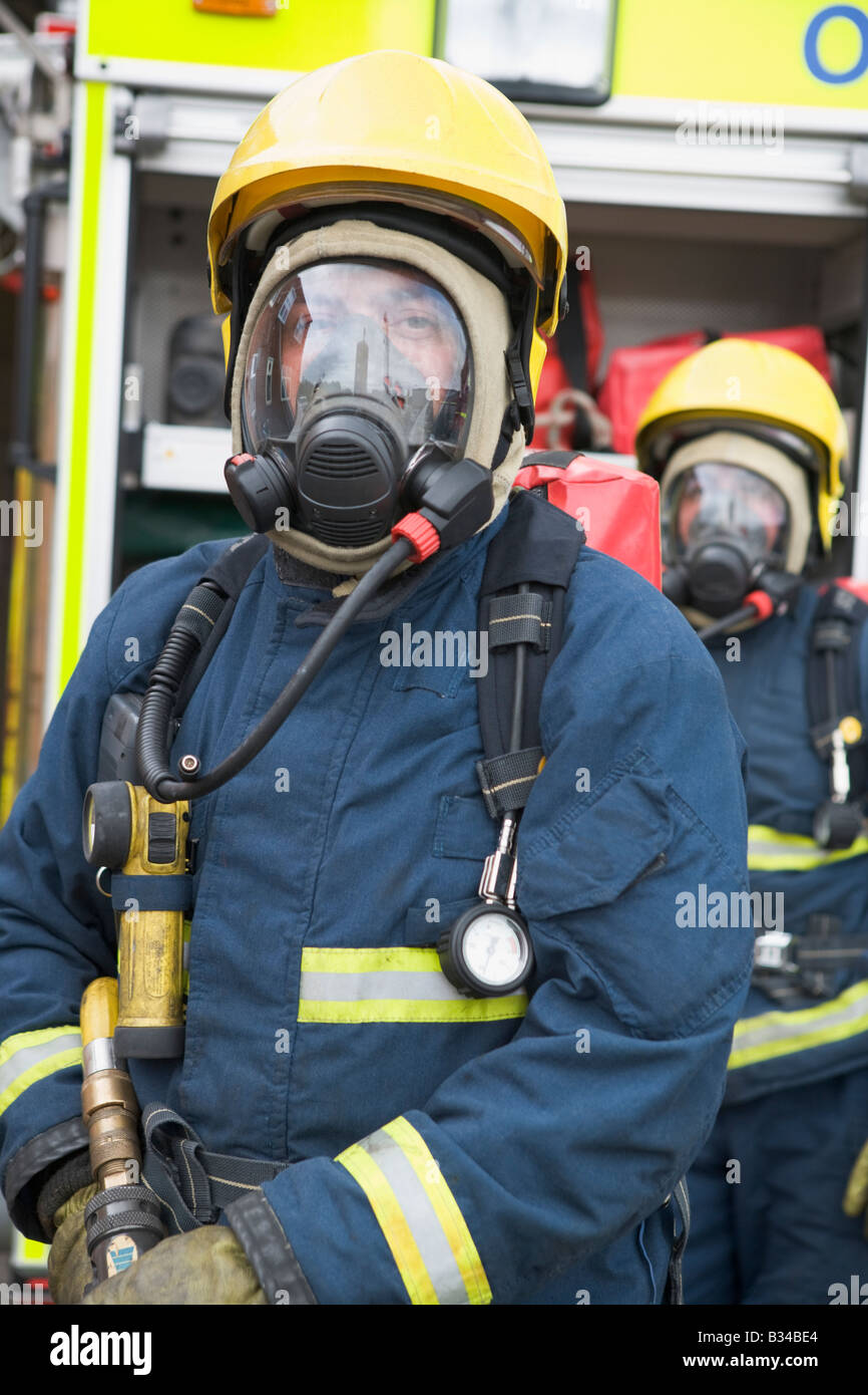 Due vigili del fuoco nelle maschere in piedi vicino a motore Fire (profondità di campo) Foto Stock