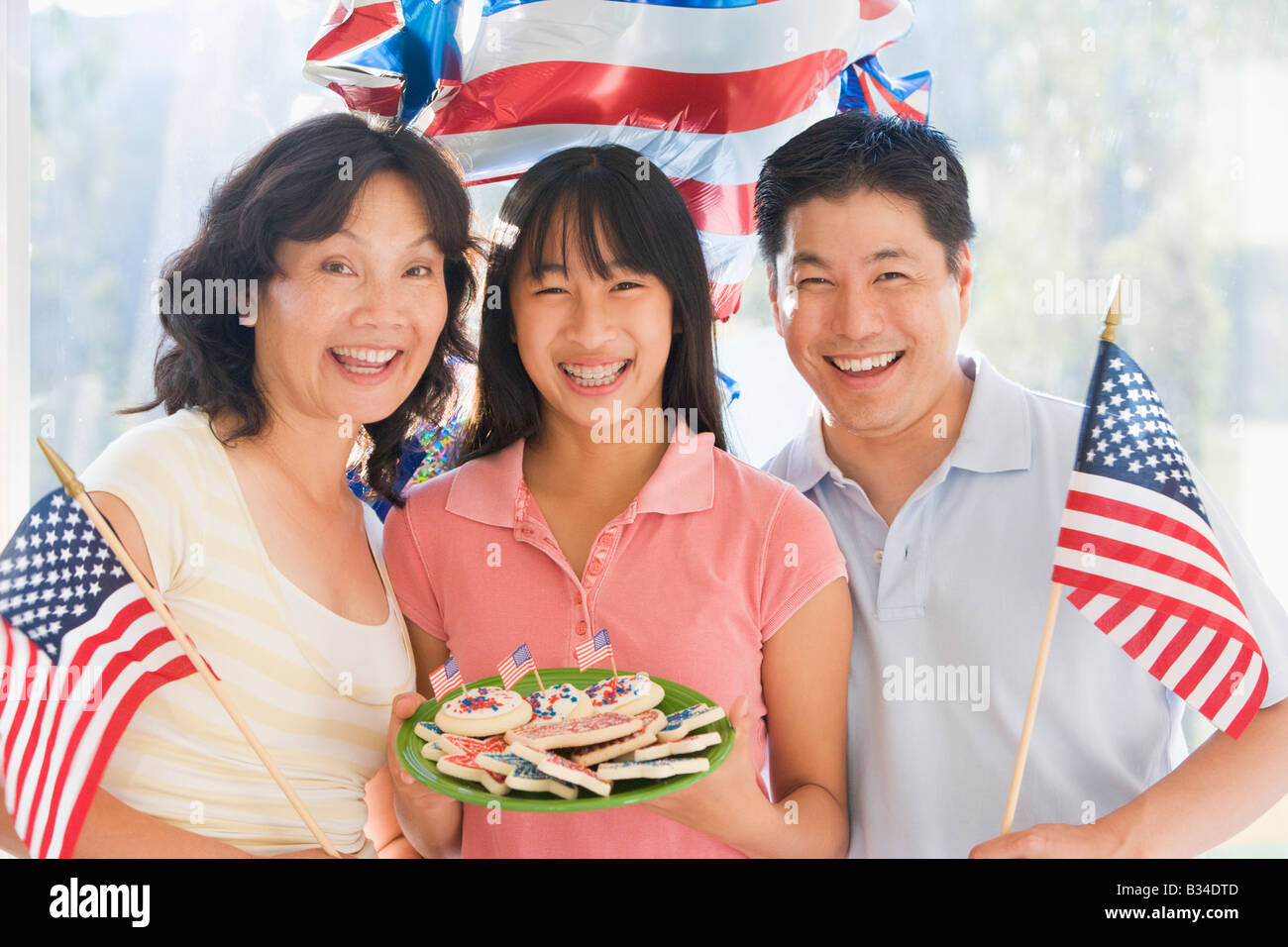 Famiglia all'aperto sul quarto di luglio con bandiere e cookie sorridente Foto Stock