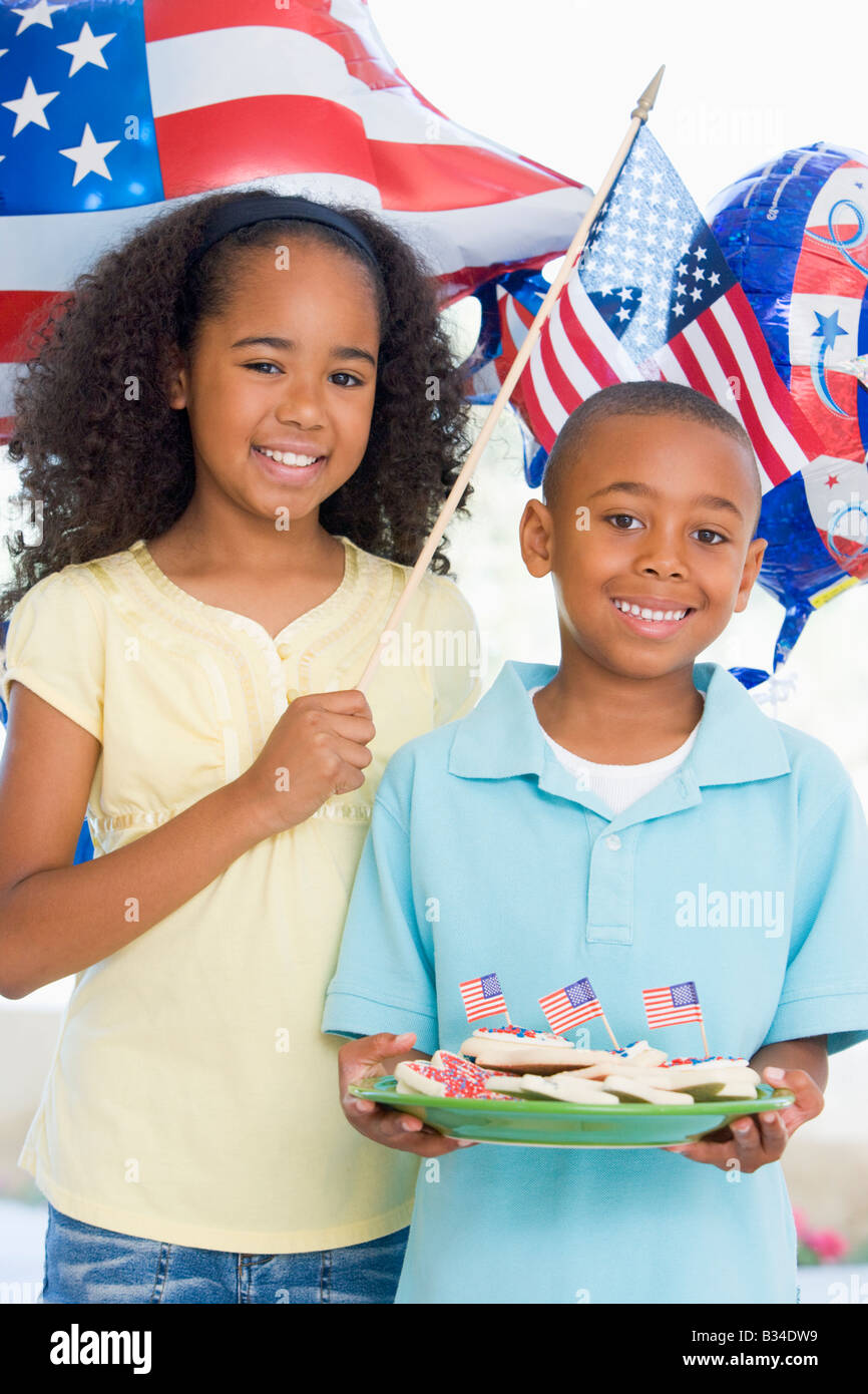Fratello e Sorella sul quarto di luglio con la bandiera e i cookie sorridente Foto Stock