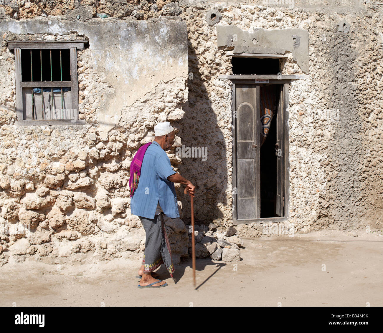 Kenya, Pate Island, Pate Village. Una lingua swahili uomo cammina verso l'ingresso di casa sua nel villaggio di patè. Tutti gli edifici in Pate ar Foto Stock
