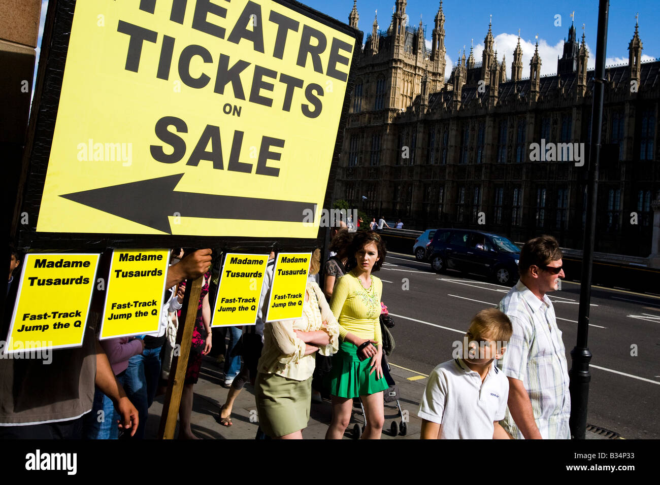 I pedoni a piedi da un uomo con un grande segno pubblicità i biglietti per il teatro in vendita in Londra, Regno Unito Foto Stock