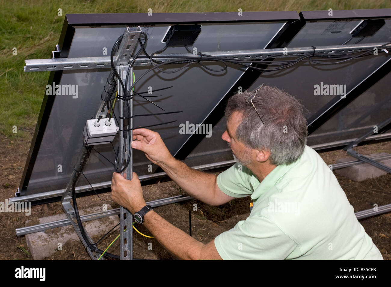 Elettricista installazione cablaggio sulla matrice di 12 ibrido solare pannelli  fotovoltaici sulle lamiere galvanizzate un telaio nel campo Costwolds REGNO  UNITO Foto stock - Alamy
