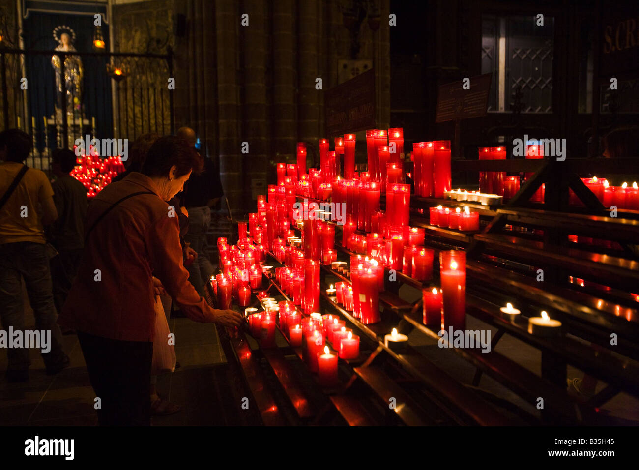 Spagna Barcellona luce donna rosso candela votiva nell interno della cattedrale di Barcellona architettura gotica costruita nel XIV secolo Foto Stock