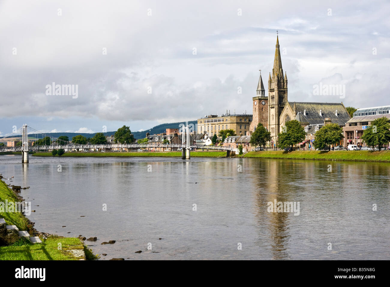 Greig Street sospensione ponte attraversa il fiume Ness in Inverness con la libera nord chiesa parzialmente nascondendo la vecchia chiesa alta Foto Stock