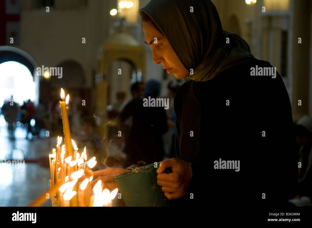 La donna georgiana illumina le candele mentre prega all'interno della Cattedrale della Santissima Trinità comunemente conosciuta come la cattedrale di Sameba a Tbilisi, Repubblica di Georgia Foto Stock