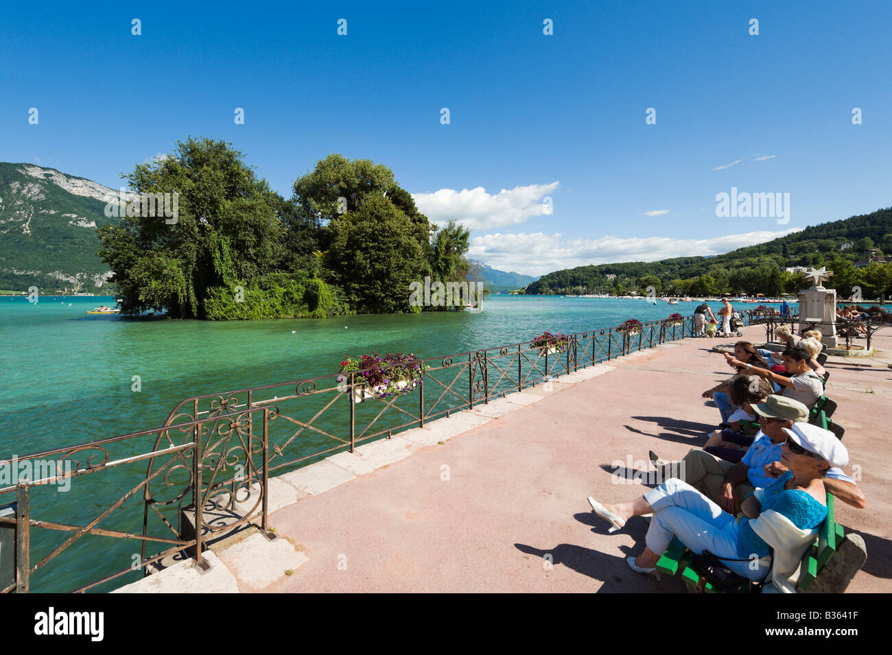 Turisti che si siedono sui banchi sulle rive del lago di Annecy, Annecy, sulle Alpi francesi, Francia Foto Stock