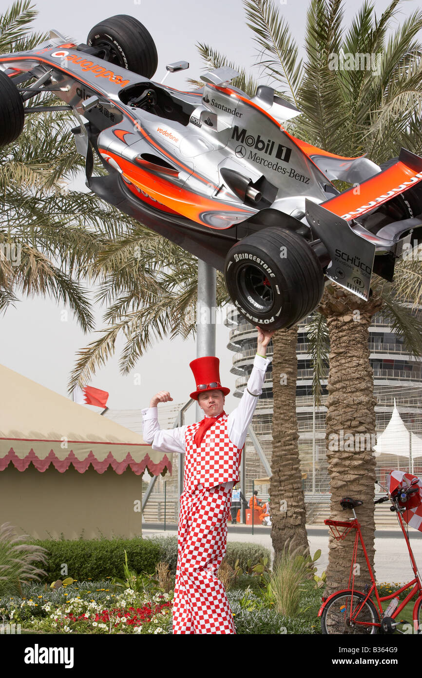 Stilt walker clown uomo forte finge di tenere Lewis Hamilton 2007 McLaren Mercedes a 2008 Bahrain F1 Grand Prix di Formula 1 Foto Stock