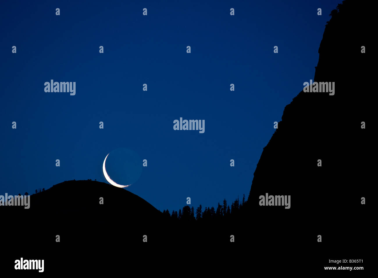 Un pre alba falce di luna sorge direttamente sulla sommità della cupola Sentinel Yosemite National Park California USA Foto Stock