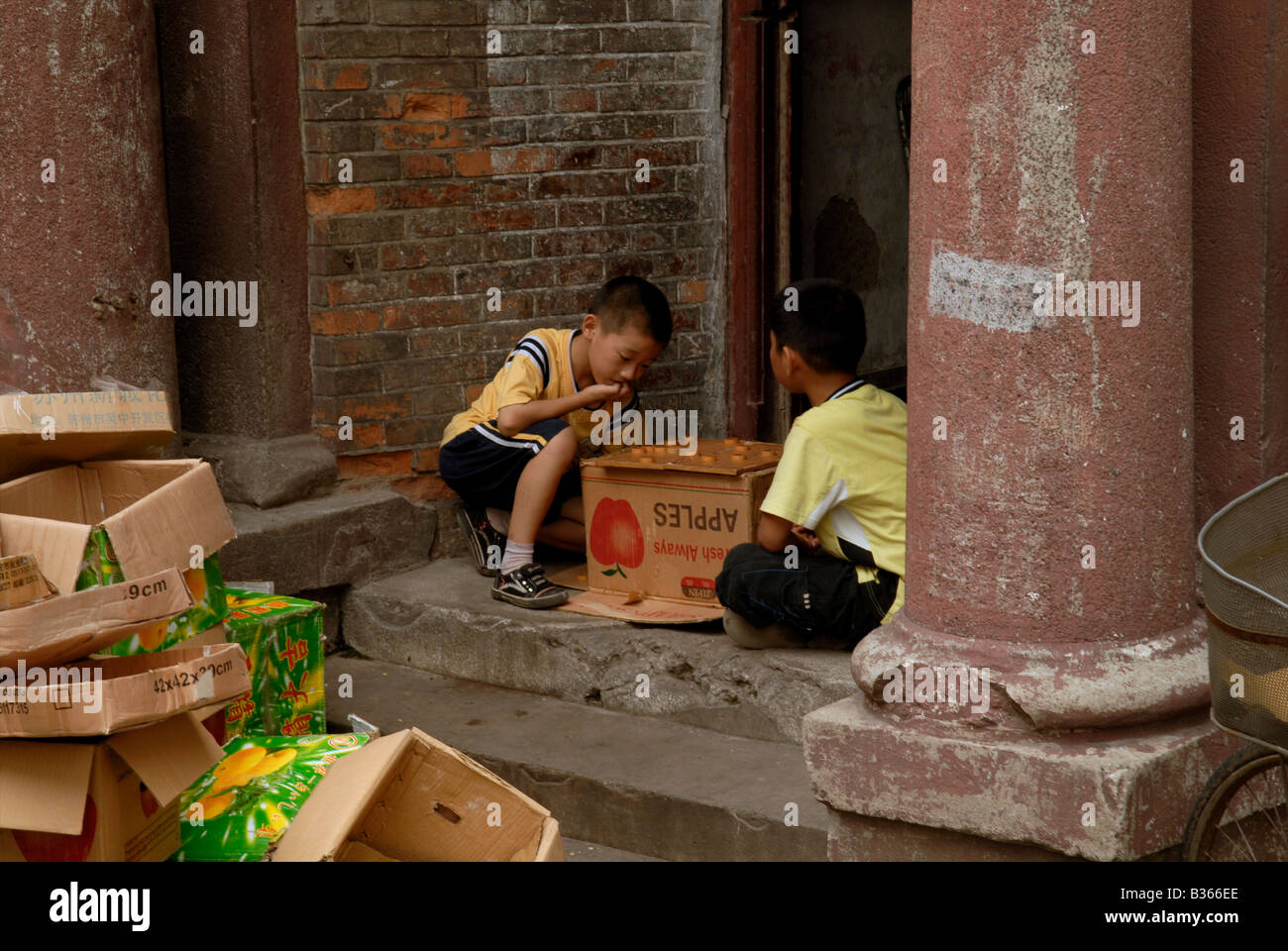 Due bambini cinesi giocare un gioco di bordo in un modo della porta di una casa in stile coloniale di Shanghai Foto Stock