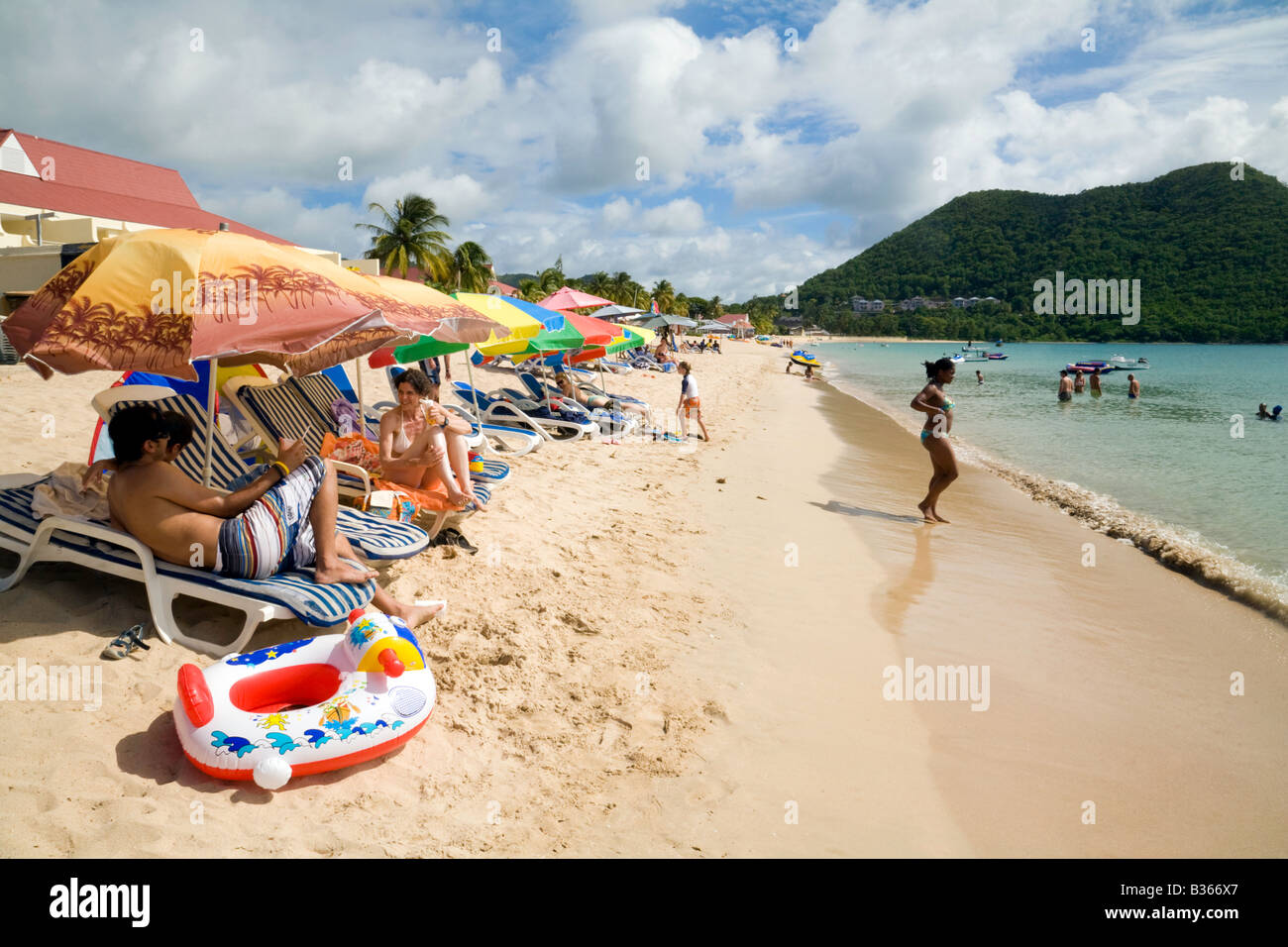 Il turista a godere il sole sulla spiaggia di Reduit, St Lucia, West Indies Foto Stock