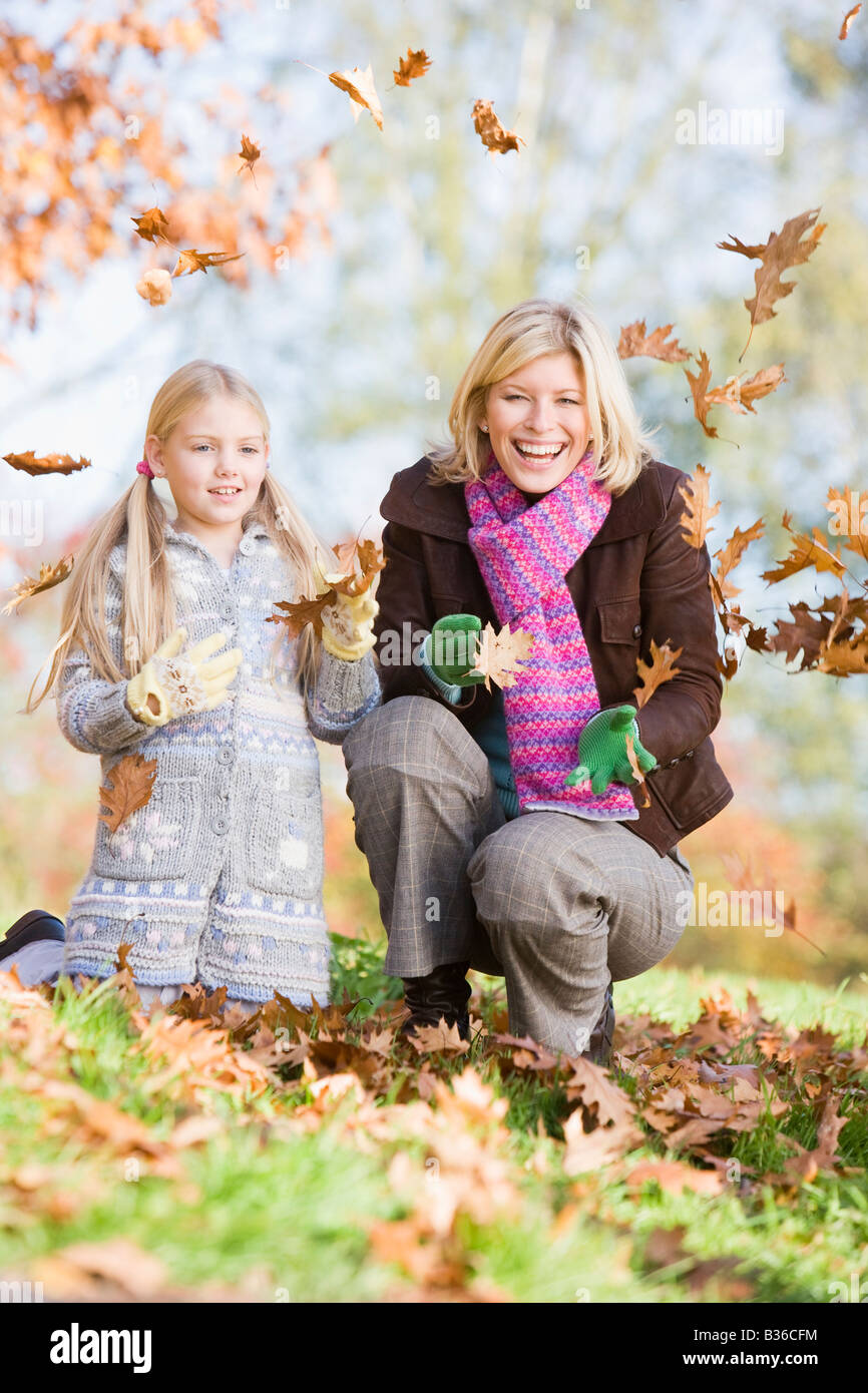 Donna e bambina all'aperto nel parco giocando in foglie e sorridente (messa a fuoco selettiva) Foto Stock