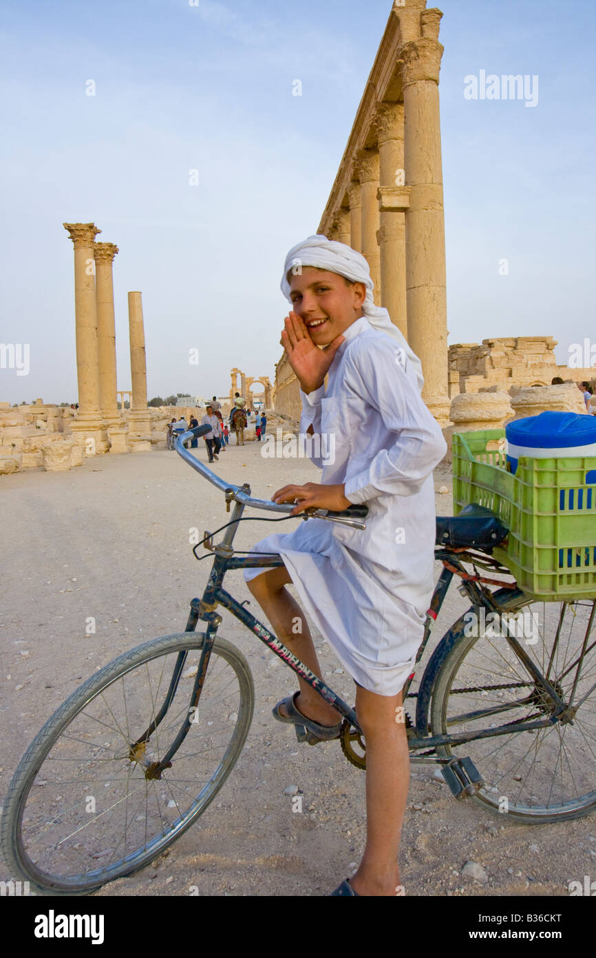 Ragazzo siriano chiamando l'acqua per la vendita in rovine Romane di Palmyra in Siria Foto Stock